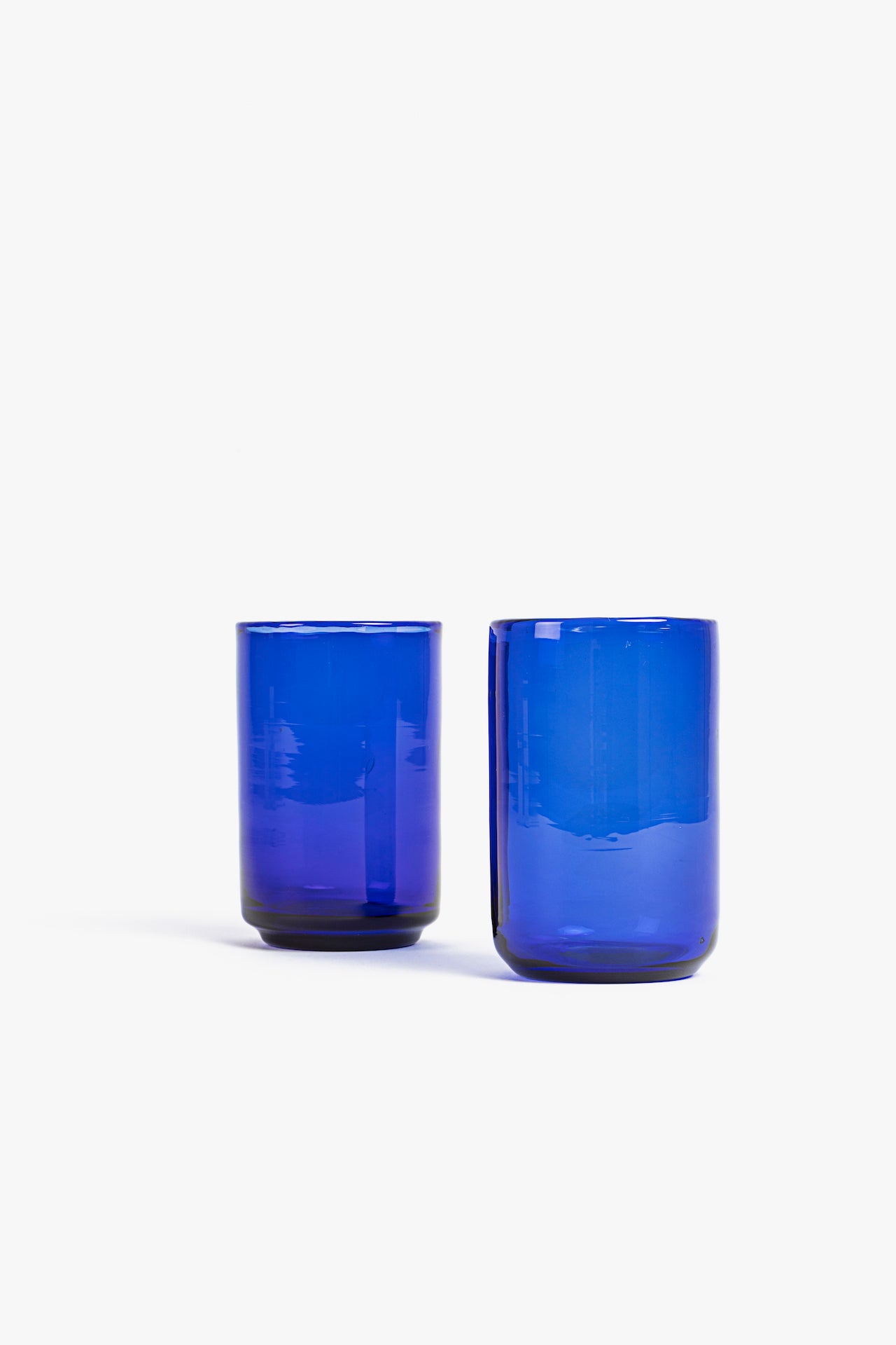 Two blue glass tumblers on a white background