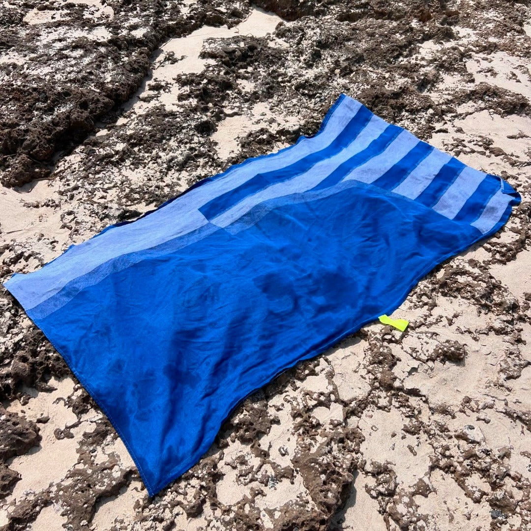Blue and white striped towel on a sandy surface