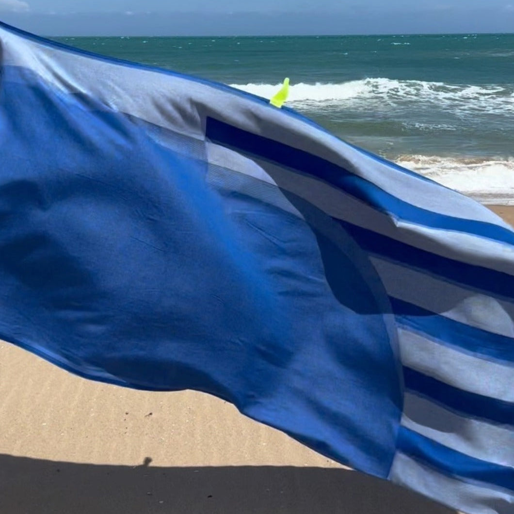 Blue striped towel on a sandy beach with ocean waves in the background