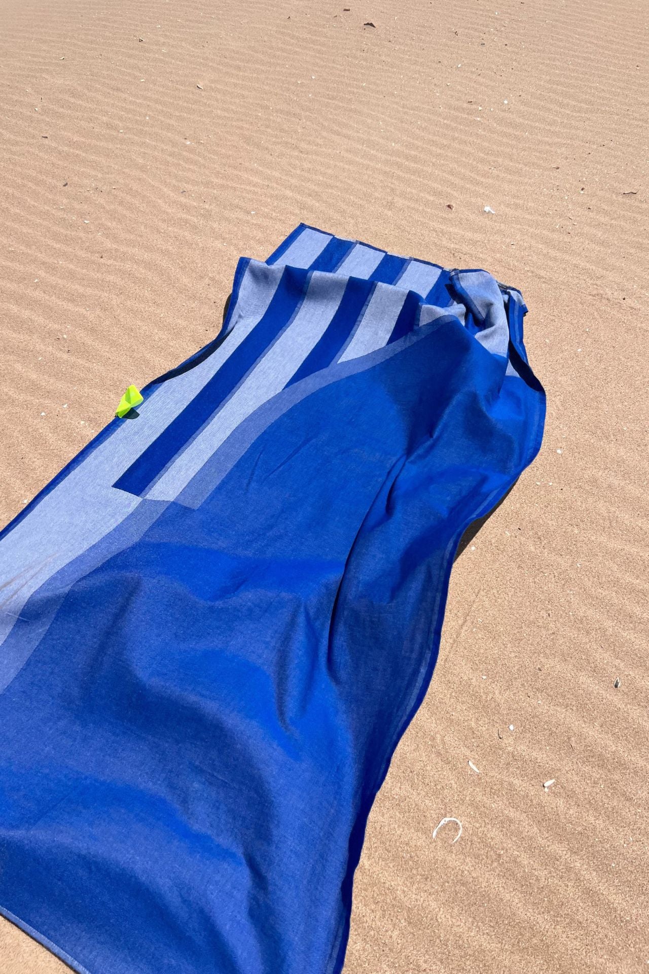 Blue and white striped towel on a sandy surface