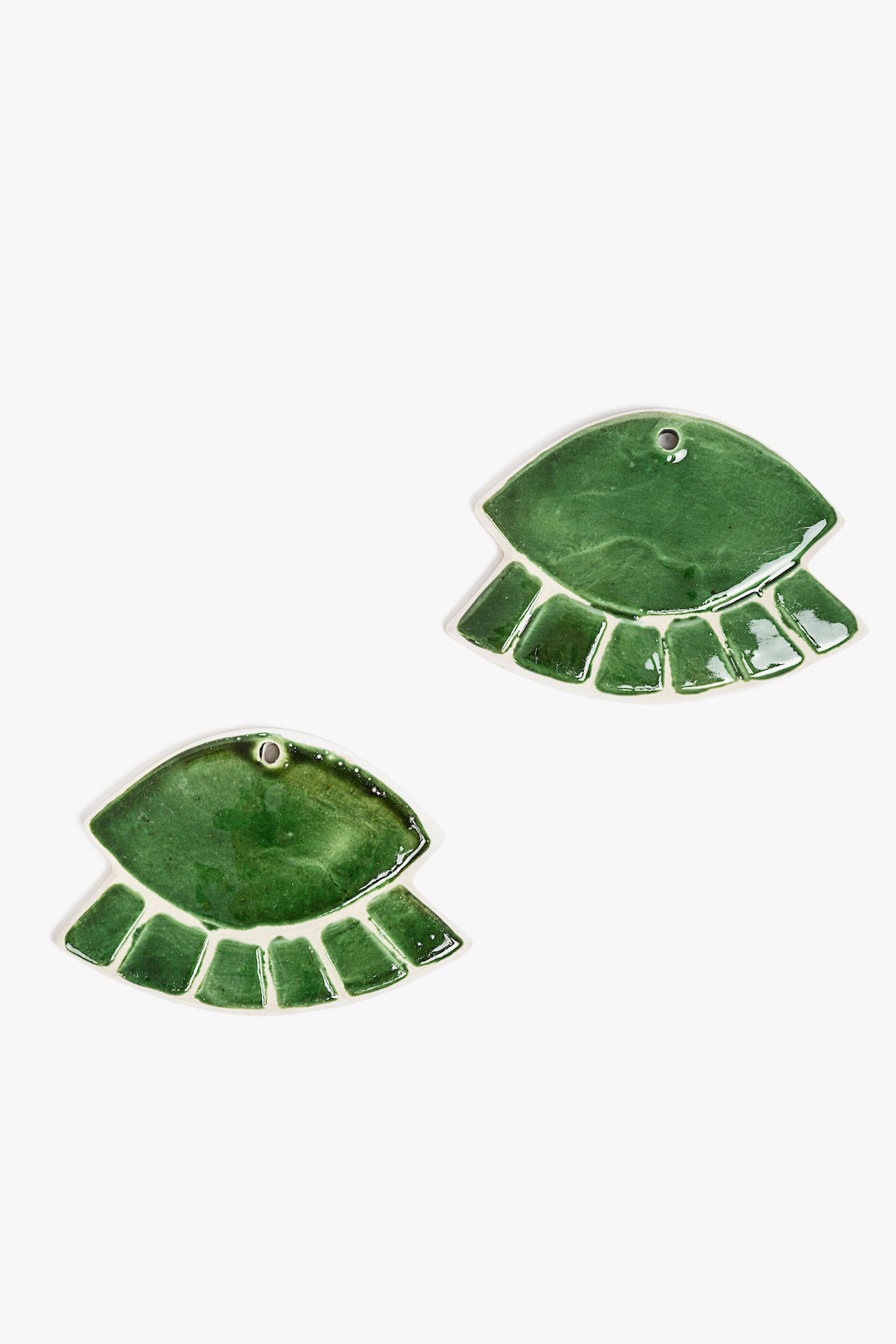 Green closed-eye-shaped ornament in ceramic on a white background