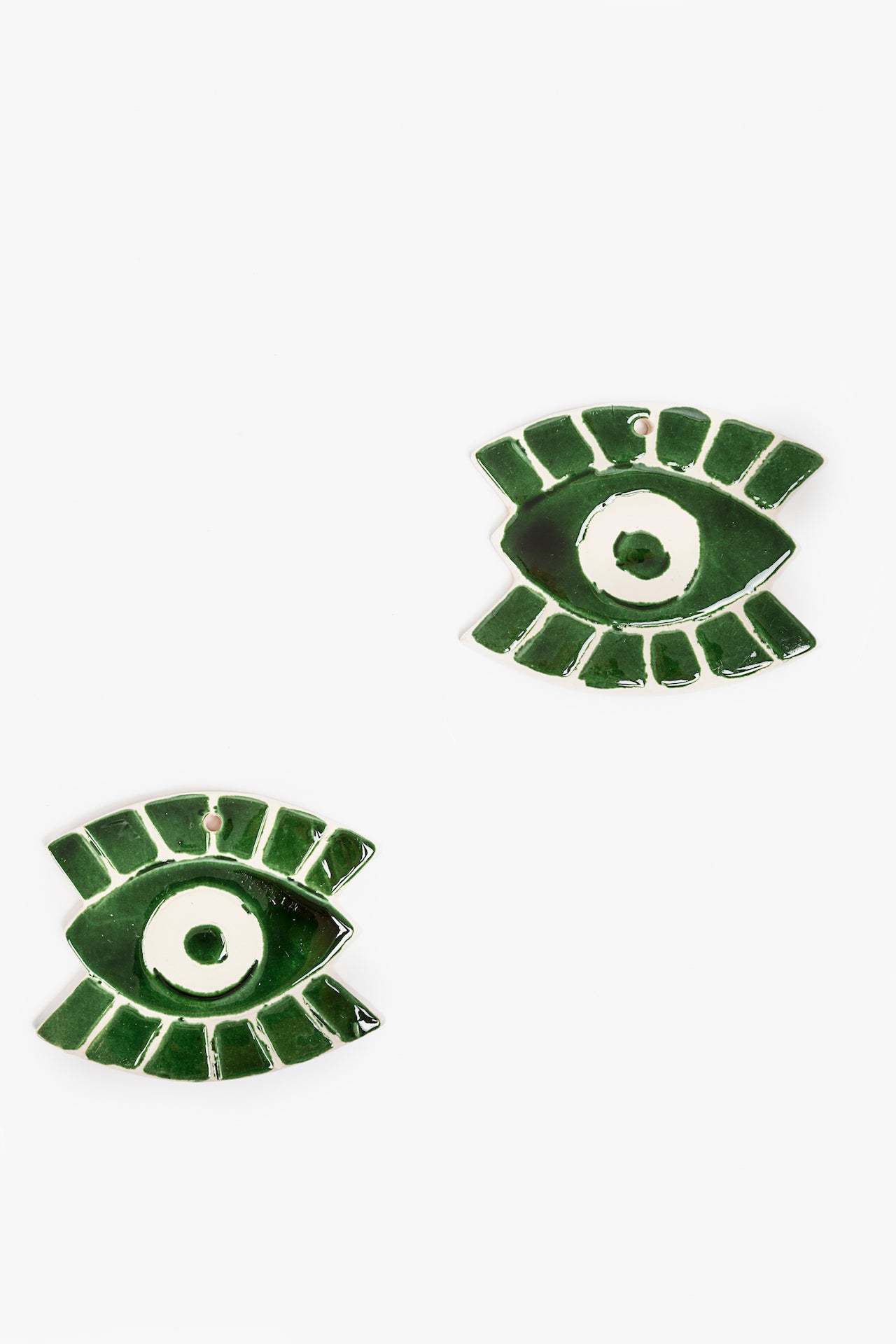 Green eye-shaped ceramic wall ornaments on a white background