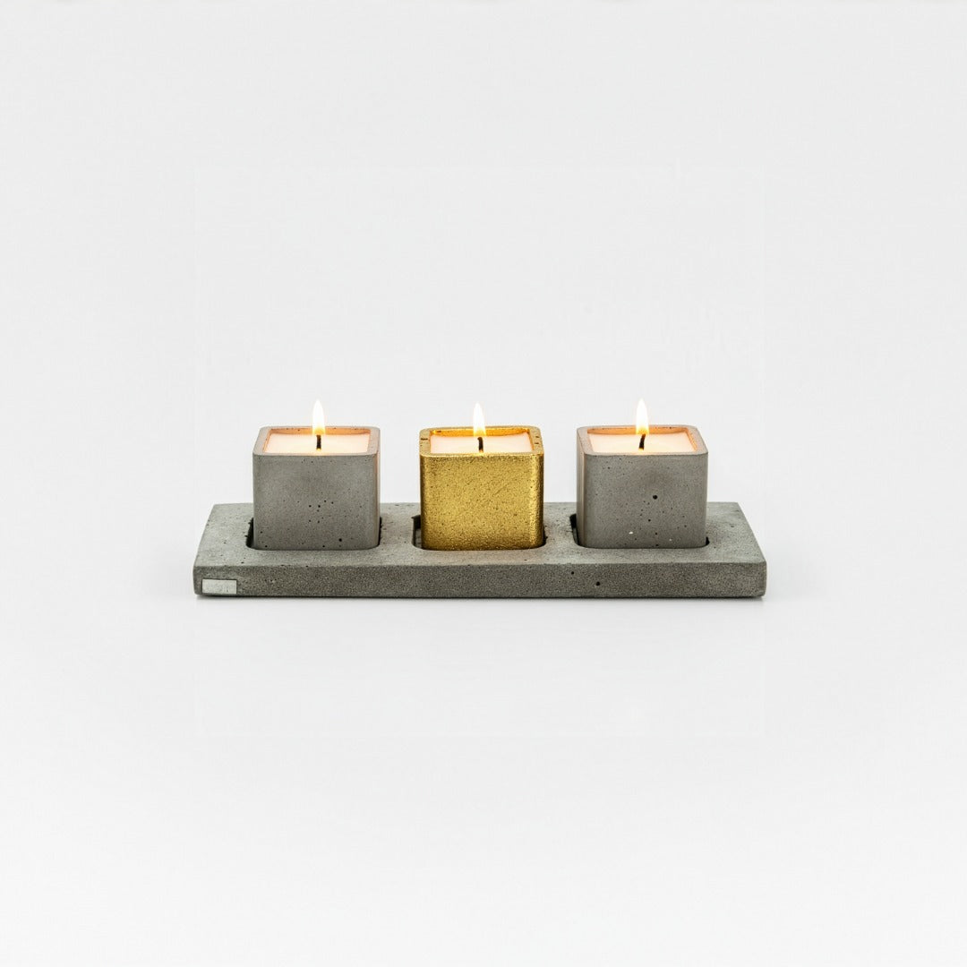 Three candles in concrete holders on a white background