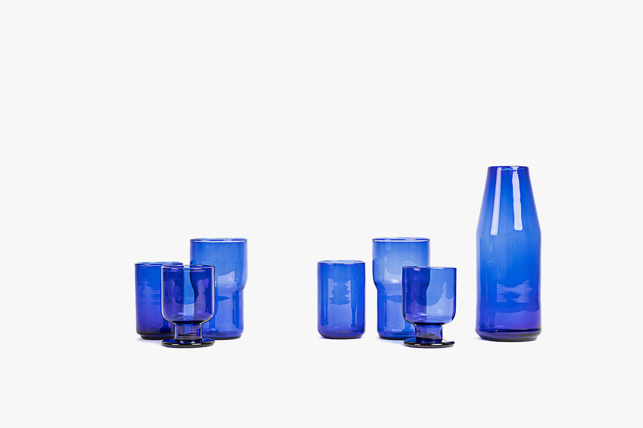 Two blue blown glass tumblers on a white background