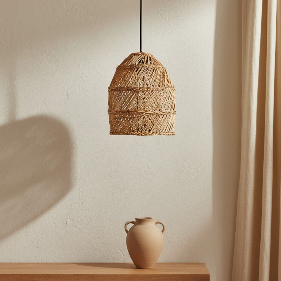 Woven seagrass pendant light hanging above a wooden surface with a ceramic vase.