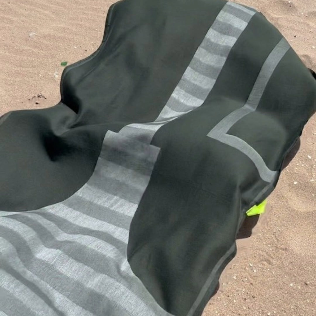 Dark green fouta plaid with reflective stripes on a sandy background